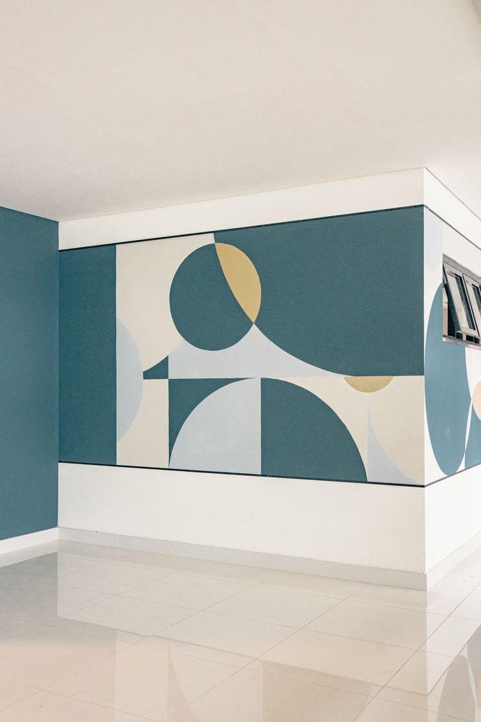 About Light-filled, modern interior featuring abstract geometric wall art on blue and white walls.